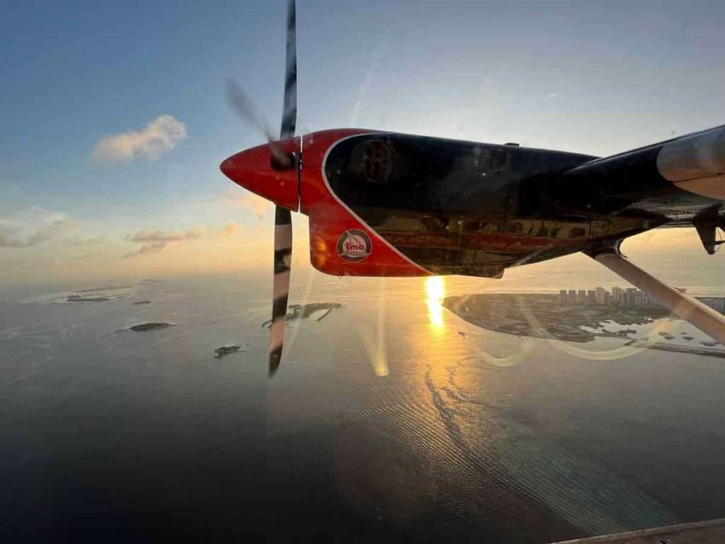 朝焼けの中モルディブの島々の上空を飛行する水上飛行機