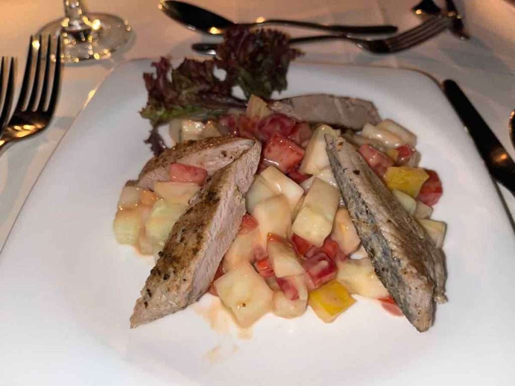 前菜の魚料理 カットされたフルーツの上にスチームされた魚がのっている