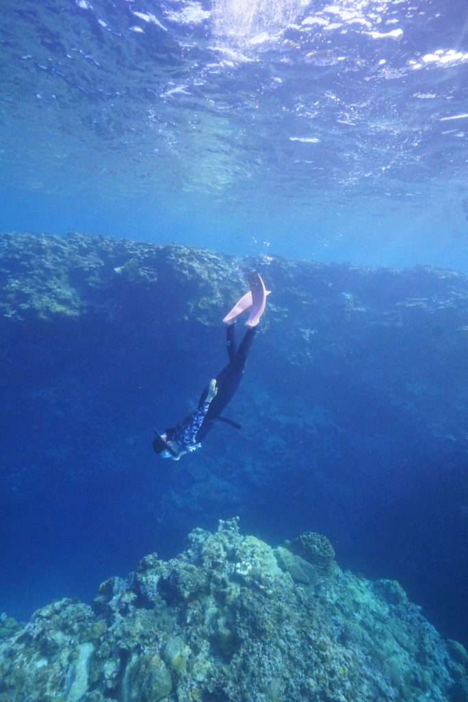 深く青い海の中を潜る女性