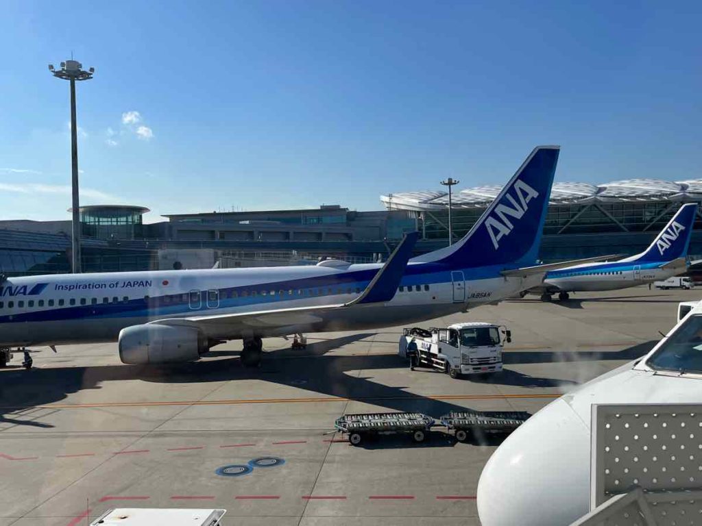 真っ青に晴れ渡った空の空港に駐機された白と青のANAの航空機
