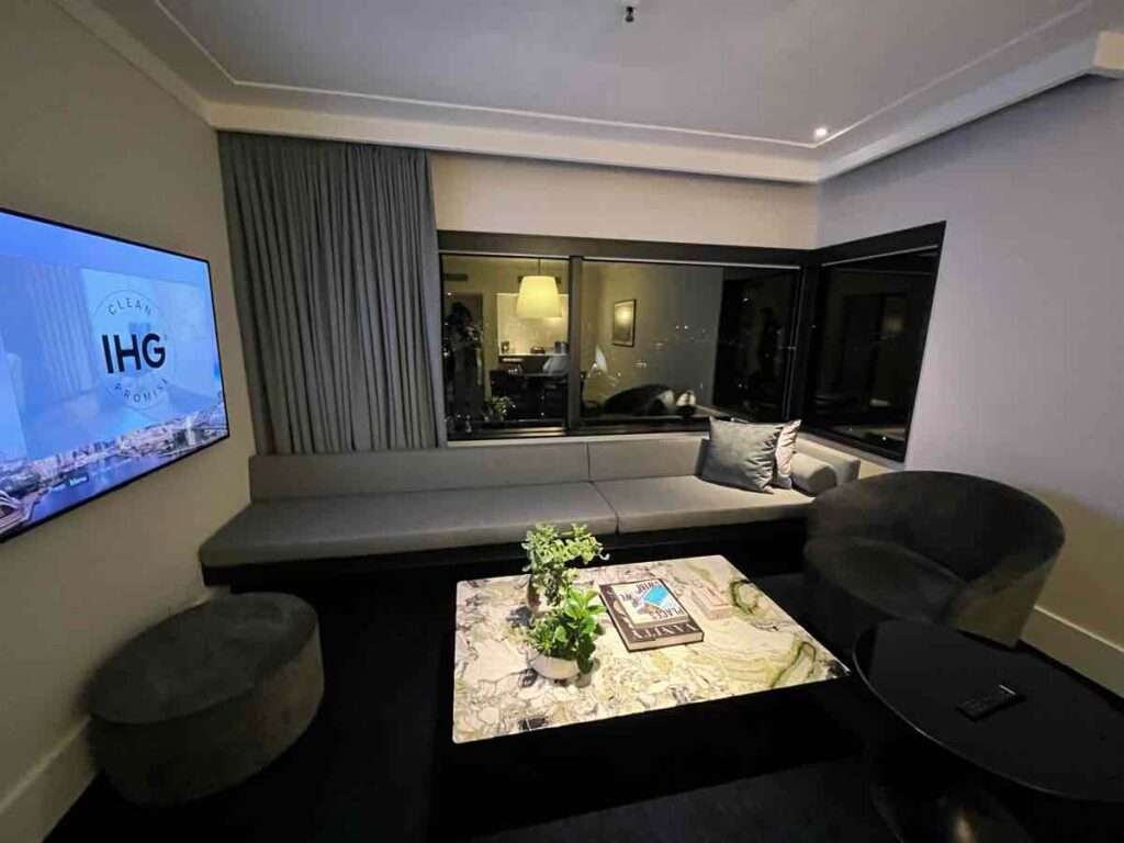 大きな壁掛けテレビのあるリビングルームと大理石のテーブルとソファ