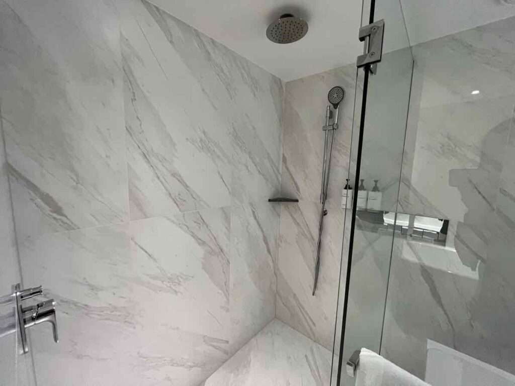 白い大理石のシャワールームとシャワーヘッド