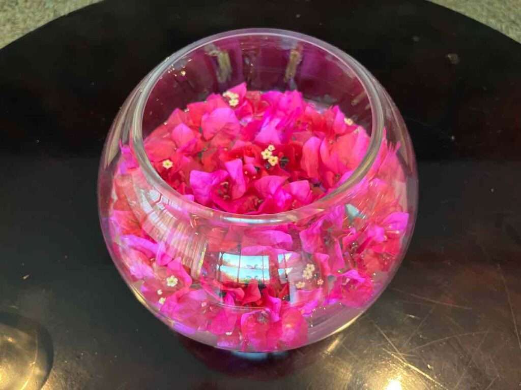 透明の丸いガラスの器にピンクの花びらが詰まっている