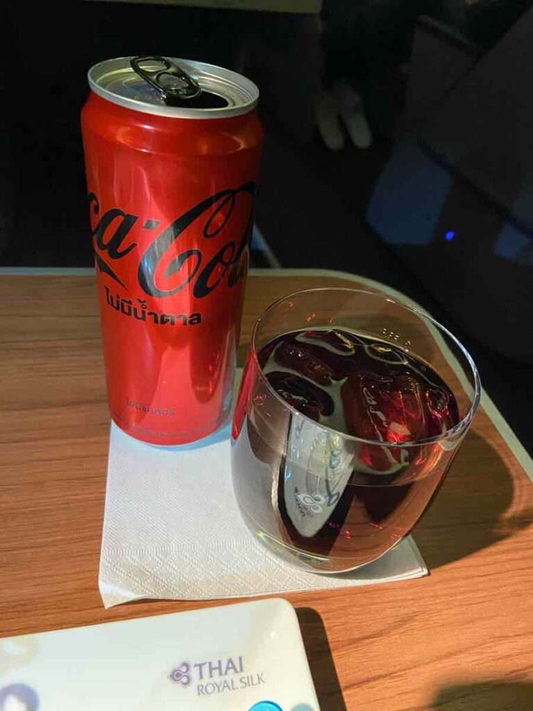 飛行機の座席テーブルに置かれたコカコーラの赤い缶