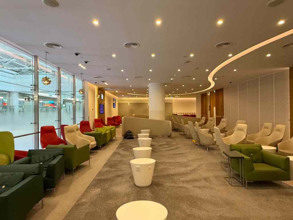オフホワイトの壁に緑と赤のソファが映えるドバイのスカイチームラウンジ。
