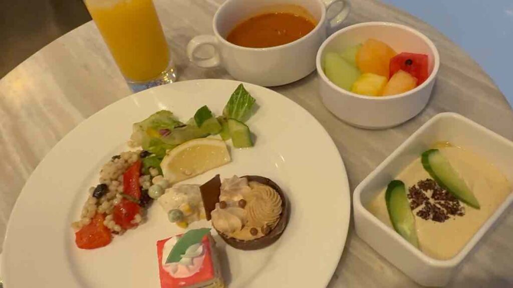 オレンジジュースとお皿に盛られたトマトクリームスープ、フムスなどの前菜とチョコレート、ラズベリーのケーキ2種。