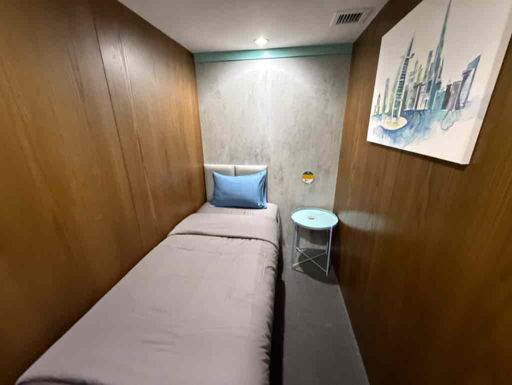 壁にブルジュハリファの絵が飾ってあるsleep 'n flyの個室内にあるベッドとサイドテーブル